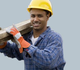 a construction worker wearing a yellow hard hat and gloves carrying some lumber