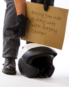 image of a person holding a sign with a motorcycle helmet sitting on the ground in front of him