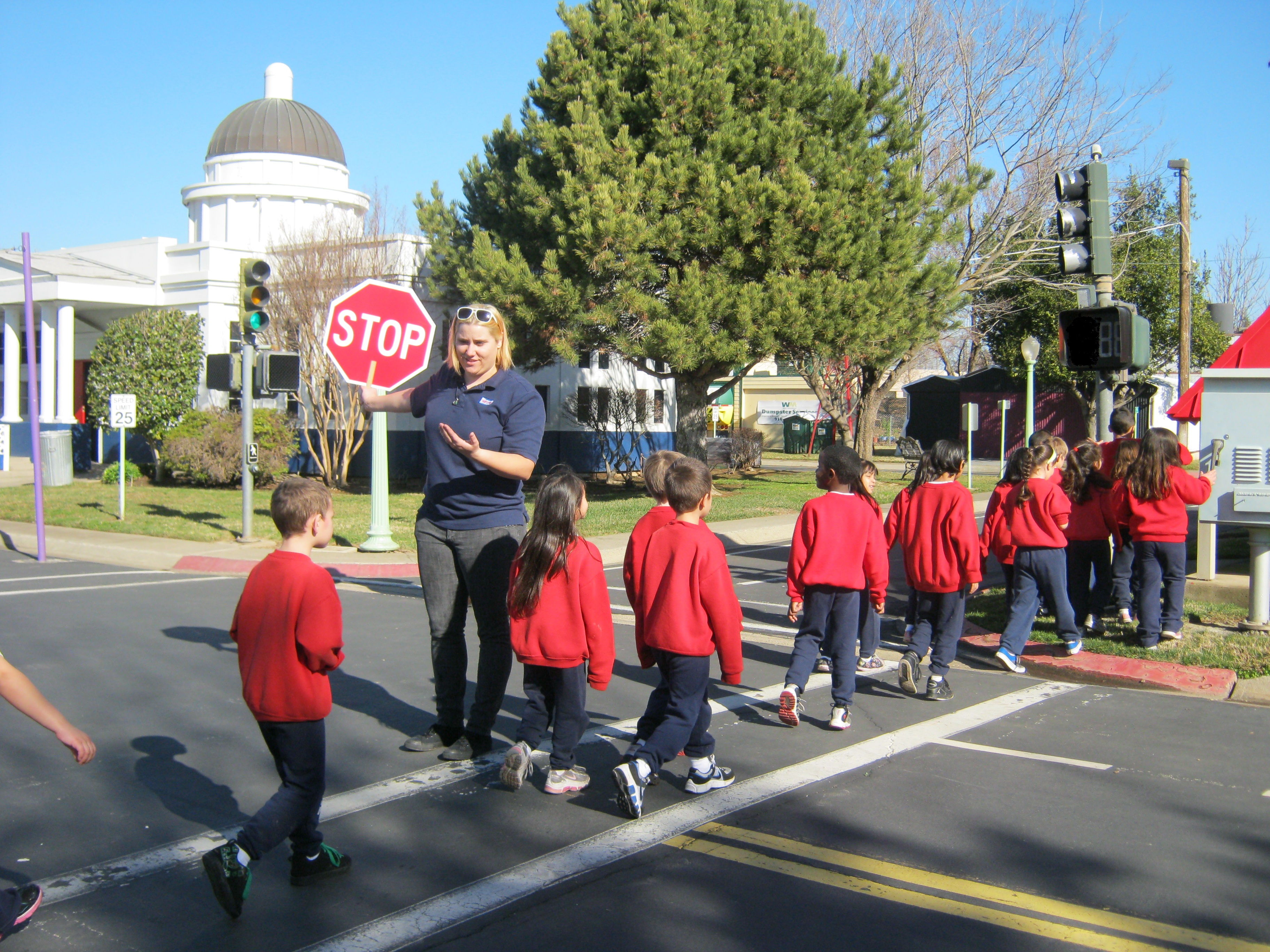 a crossing guard safely escorting children in red shirts across the street